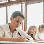 studenti Trojského gymnázia ve třídě, vyučovací hodina, studenti píšící si poznámky